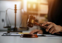 Judge's hand holding a wooden gavel above a sound block