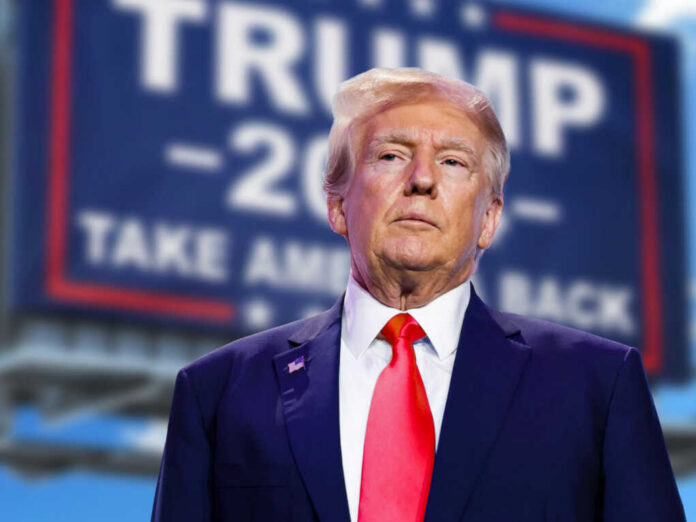 man in suit with red tie standing before a blurred campaign-style sign