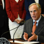 A person speaking at a podium with others behind