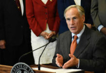 A person speaking at a podium with others behind
