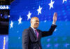 Person waving in front of a starry blue background