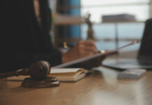 Judge's gavel on desk with person writing in background