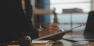 Judge's gavel on desk with person writing in background
