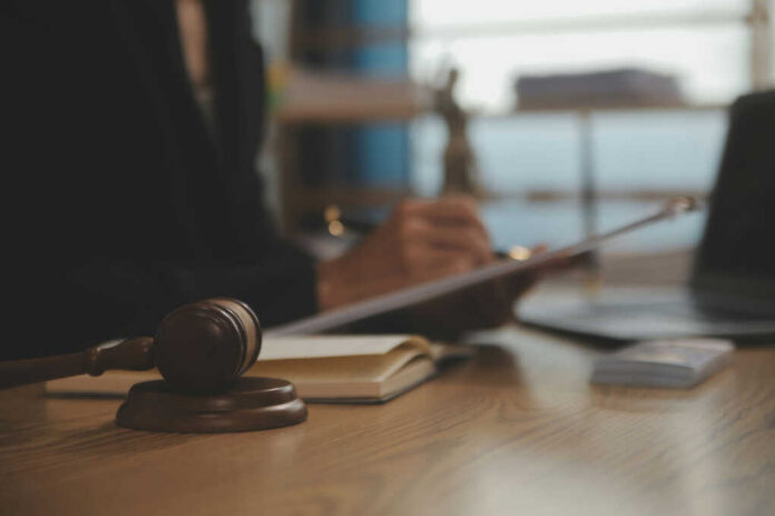 Judge's gavel on desk with person writing in background