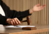 Judge's hand striking a wooden gavel on a block