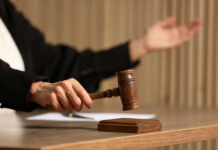 Judge's hand striking a wooden gavel on a block