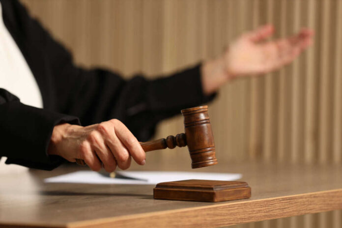 Judge's hand striking a wooden gavel on a block