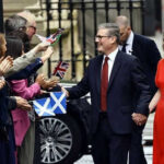 Couple holding hands greeting people waving flags