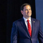 Man in suit with red tie on stage