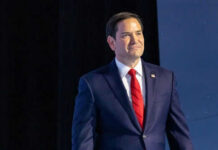 Man in suit with red tie on stage