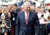 Smiling man in suit surrounded by people outdoors
