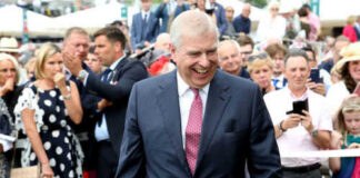 Smiling man in suit surrounded by people outdoors
