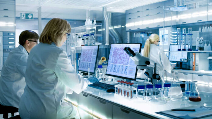 Scientists working at computers and microscopes in a modern laboratory