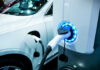 Electric vehicle charging at a station with a white car in the background