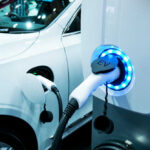 Electric vehicle charging at a station with a white car in the background