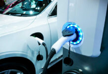 Electric vehicle charging at a station with a white car in the background