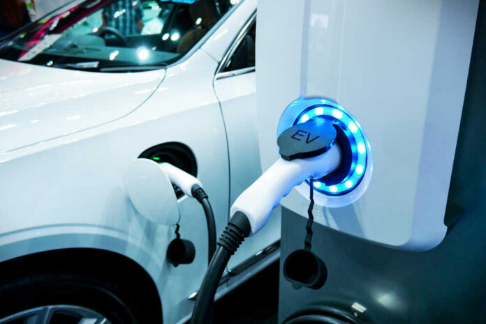 Electric vehicle charging at a station with a white car in the background