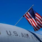 U.S. Air Force aircraft with an American flag waving against a blue sky