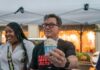 man holding a cup of ice cream under a canopy