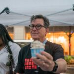 man holding a cup of ice cream under a canopy