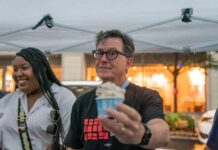 man holding a cup of ice cream under a canopy
