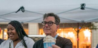 man holding a cup of ice cream under a canopy