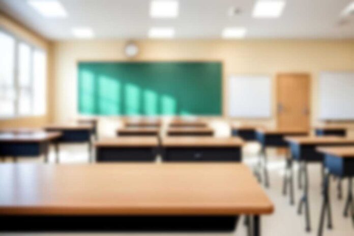Empty classroom with desks, a green chalkboard, and natural light