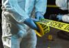Forensic investigator in protective gear handling crime scene tape