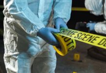 Forensic investigator in protective gear handling crime scene tape