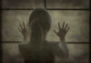 A silhouette of a child with hands pressed against a window