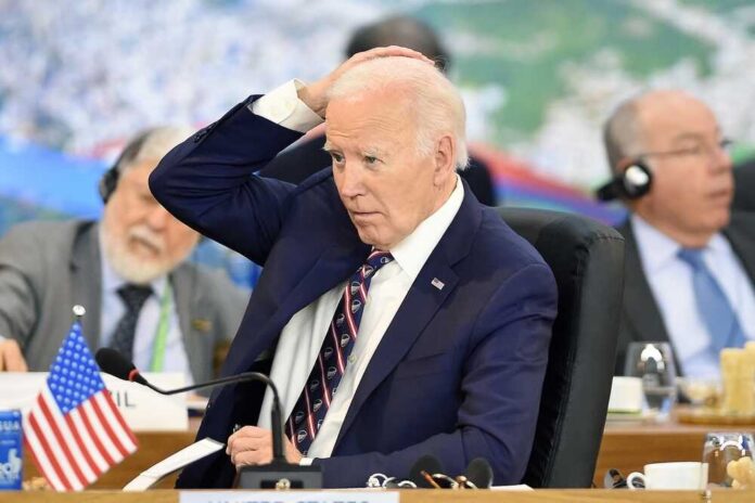 A man in a suit with a concerned expression during a meeting