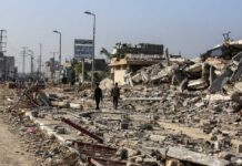 Two individuals walking through a devastated urban area filled with rubble