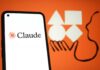 Smartphone displaying the logo of Claude against an orange background with abstract shapes