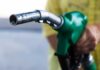 Close-up of a hand holding a green fuel pump nozzle
