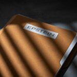 A brown file folder with the name 'EPSTEIN' on it, partially illuminated by light and casting shadows.