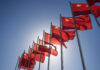 Multiple Chinese flags waving against a clear blue sky