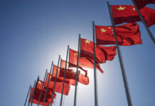 Multiple Chinese flags waving against a clear blue sky