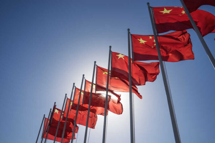 Multiple Chinese flags waving against a clear blue sky