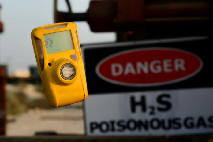 Yellow gas detector with danger sign in background