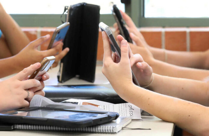 Students' hands holding smartphones in a classroom