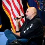 Man in a hoodie speaks into a microphone on stage