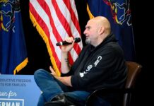 Man in a hoodie speaks into a microphone on stage