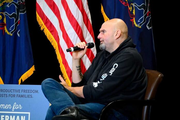 Man in a hoodie speaks into a microphone on stage