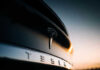 Closeup of Tesla car logo at sunset