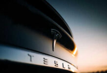 Closeup of Tesla car logo at sunset