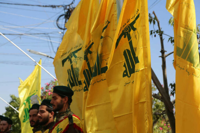 Men standing with yellow flags wearing green berets