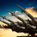 Cruise missile launcher with missiles pointed upwards against a sunset sky