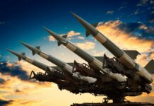 Cruise missile launcher with missiles pointed upwards against a sunset sky