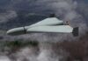 Flying wing drone with pusher propeller over foggy forest
