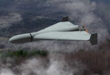 Flying wing drone with pusher propeller over foggy forest